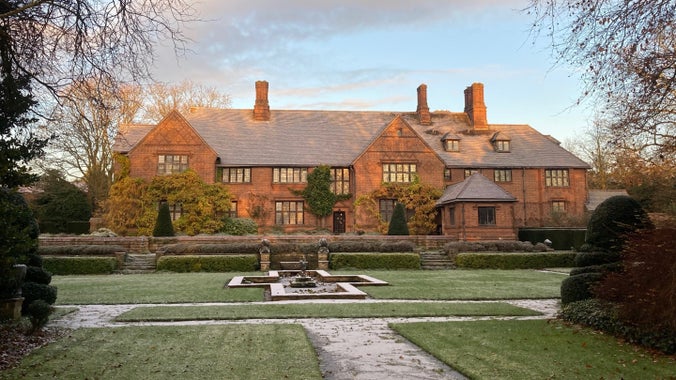 Looking across a frosty lawn and pond towards a large bricked house